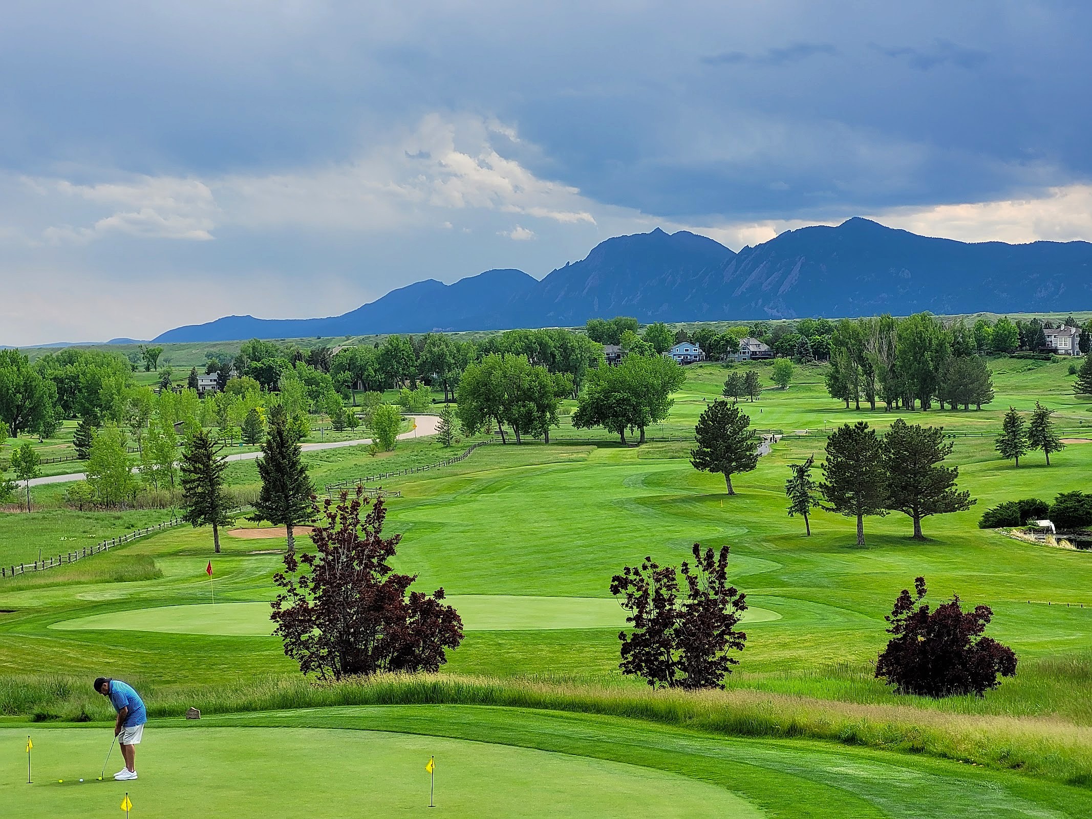 Golfer putting on Lake Valley course green with Flatirons mountains in the background
