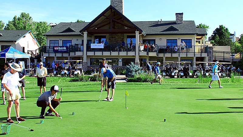 Golfers at Lake Valley practice facility with the clubhouse in the background